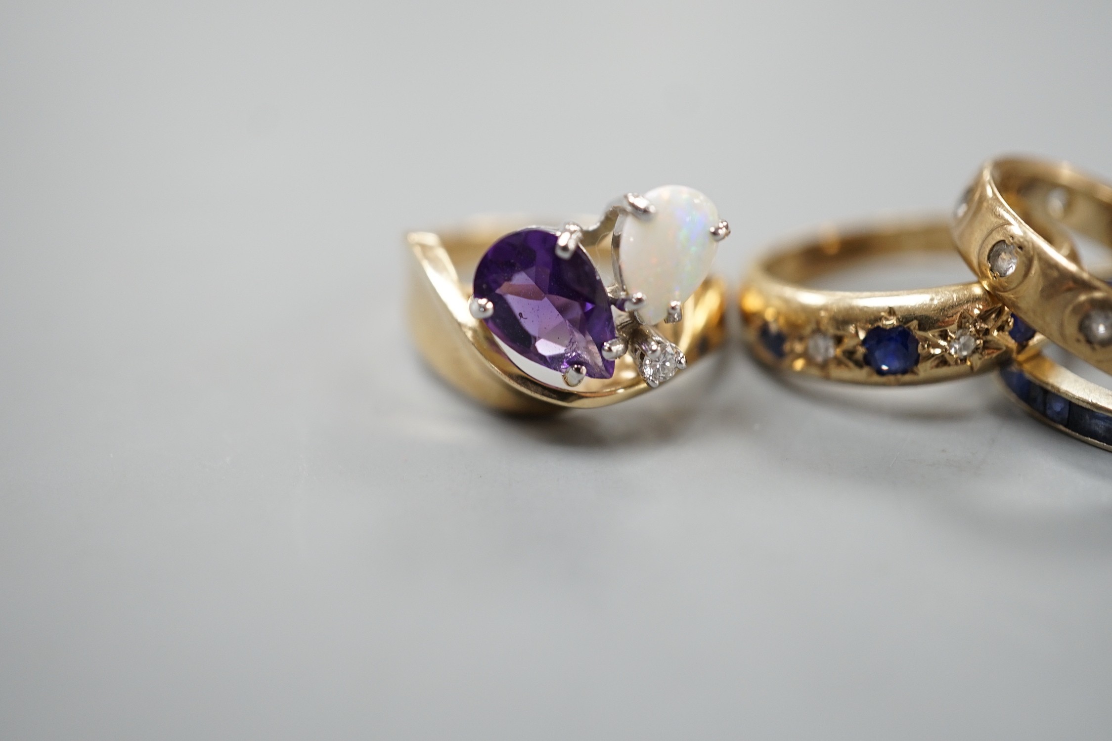 A 10k yellow metal, amethyst, white opal and diamond set dress ring, size N, gross weight 4.6 grams, two 9ct and gem set rings and a white metal and sapphire? set full eternity ring, gross weight 8.2 grams.